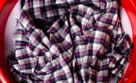 Washing color clothes shirt in basin enemale powdered detergent, top viewの写真素材