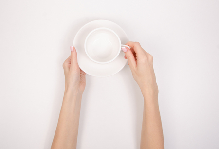 White saucer cup in hand isolated on a white background. Top viewの写真素材