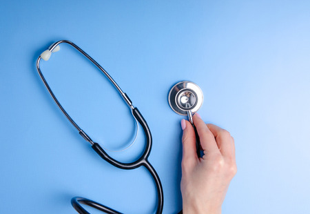Medical Concept. Top view of stethoscope in hand on blue background. Flat lay and copy spaceの写真素材
