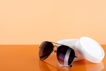 Sunglasses fashion summer accessory, whit  jar of moisturizing cream on orange backgroundの写真素材