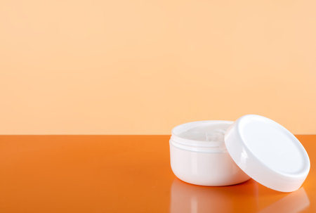 White jar of cream beauty on orange backgroundの写真素材