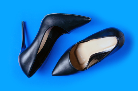 Black female high heel shoes on blue background, top viewの写真素材