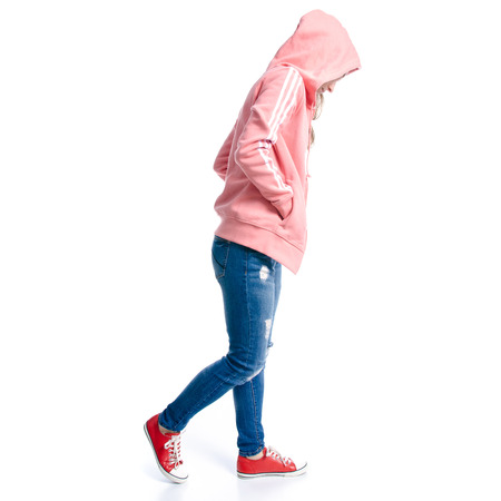 Woman in jeans and pink jacket, sneakers goes isolated on white backgroundの写真素材