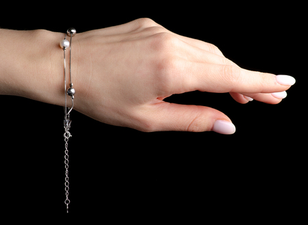 Jewelry silver bracelet with pearls on the hand isolated on a black background.の写真素材