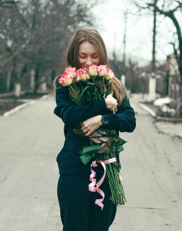 Woman with bouquet of pink roses in hand in the streetの写真素材