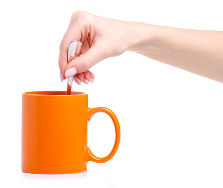 Orange cup mug with tea spoon in hand isolated on a white backgroundの写真素材