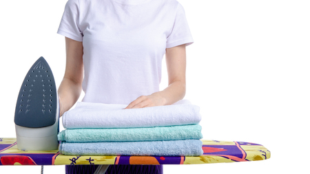 Woman ironing laundry towels on iron board on white background isolationの写真素材