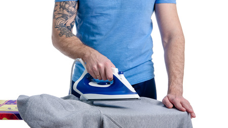 Iron in male hand on iron board ironing linen on white background isolationの写真素材