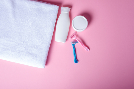 White towel, jar cream, lotion, razor, roller deodorant soft beauty on pink background, top viewの写真素材