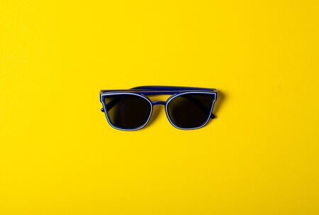 Blue sunglasses fashion on color yellow background, top viewの写真素材