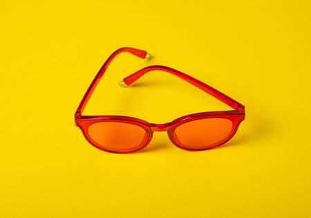 Red sunglasses fashion on yellow background, top view