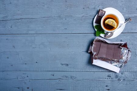White cup of mint tea with lemon and chocolate on a blue gray wooden backgroundの写真素材