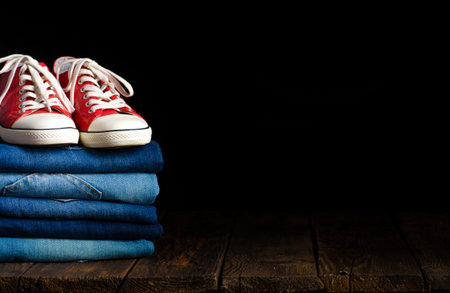 fashionable clothes. pile of jeans, red sneakers on a wooden backgroundの写真素材