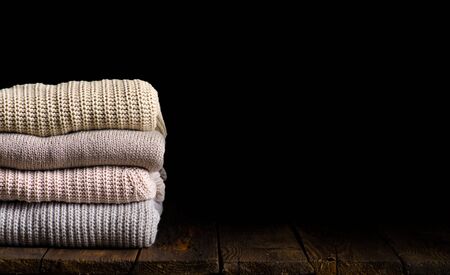 stack of clothes from knitted knitwear on a wooden background, toned imageの写真素材