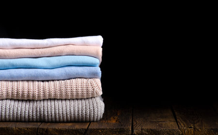 stack of clothes from knitted knitwear on a wooden background, toned image