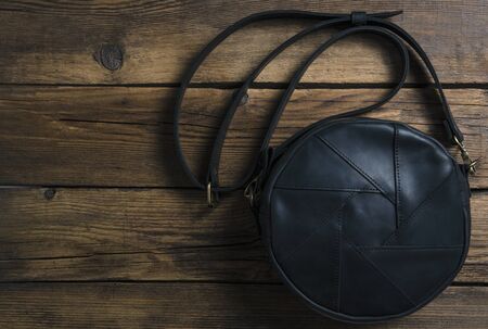 Black leather female bag on wooden background, top viewの写真素材