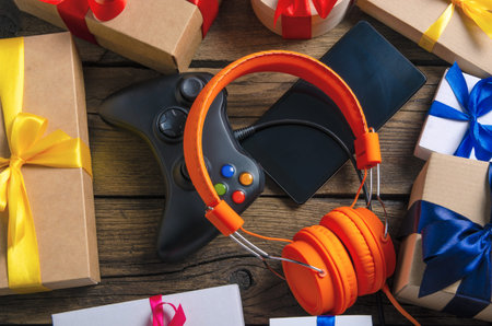 Orange headphones music audio, gamepad, smartphone, mobile phone, box with ribbon bow gift on wooden...