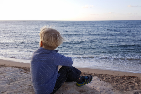 Boy sitting on rocks near sea shore waiting. Haifa beach. Israelの写真素材
