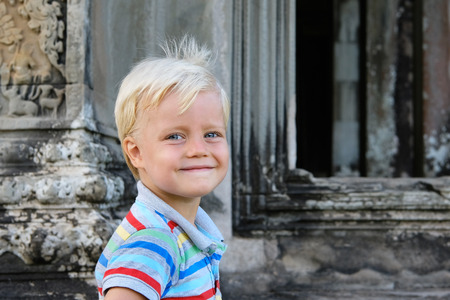 Cute little boy 4 years old blond hair sitting outdoor. Angkor, Cambodiaの写真素材