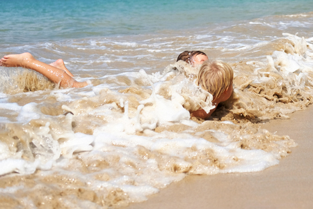 Two boys play in waves of surf, Thailand. Concept: family vacationの写真素材