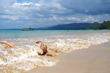 Two boys play in waves of surf, Thailand. Concept: family vacationの写真素材