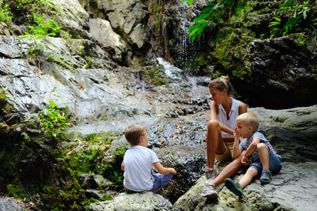 Children with mother relaxing in nature near rockの写真素材
