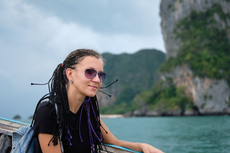 Young woman sitting in longtail taxi boat, looking seascapes in Thailand