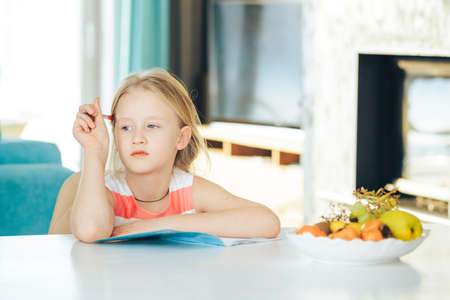 little girl at the table with a notebook, doing homework.の写真素材
