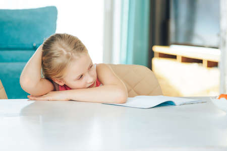 little girl at the table with a notebook, doing homework.の写真素材