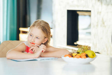 little girl at the table with a notebook, doing homework.の写真素材