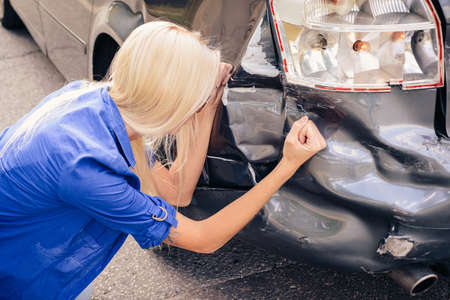 The girl in hysterics hits the broken car with her hand.の写真素材