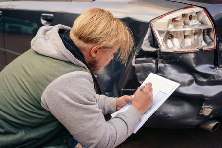 The agent examines the broken car and makes a Protocol of insurance.の写真素材