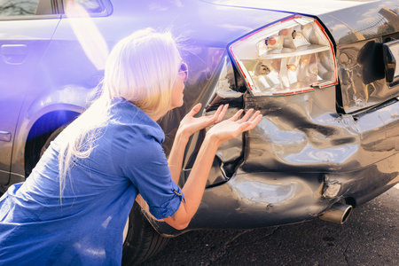 The girl sits at the broken car and thinks what to do.