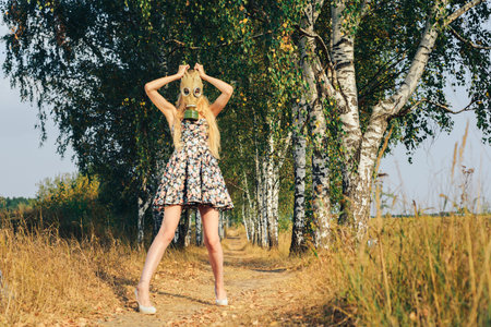 A girl in a dress walking in nature wears a gas mask. The concept of environmental pollution, viruses, and epidemics.の写真素材