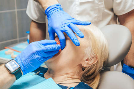 Prosthetics of the removable jaw of an elderly woman. Close-up of the doctor trying on a sample.の写真素材