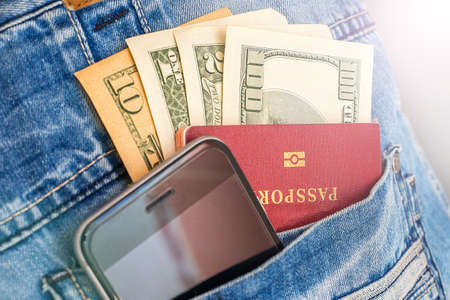Cash bills stick out of the pocket with a mobile phone and passport. The concept of travel.の写真素材