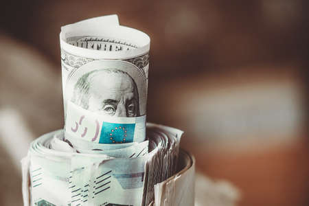 100 dollar bill with President Benjamin Franklin, Peeps out of a pack of euros, covering his face with the flag of the European Union.の写真素材