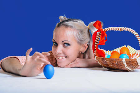 Cheerful girl with Easter eggs on a blue background is ready to celebrate Easter.の写真素材