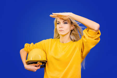 Carpenter girl with a protective helmet on a blue background.の写真素材