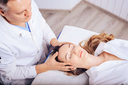 A young girl at a doctor 's appointment with an osteopath, treating curvature of the spine of the cervical departments.の写真素材