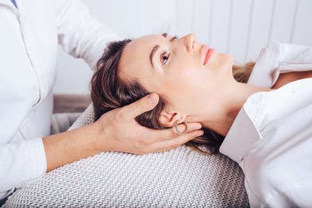 A young girl at a doctor 's appointment with an osteopath, treating curvature of the spine of the cervical departments.の写真素材