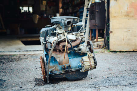 Close-up of an old engine removed from the car and lying near the garage.の写真素材