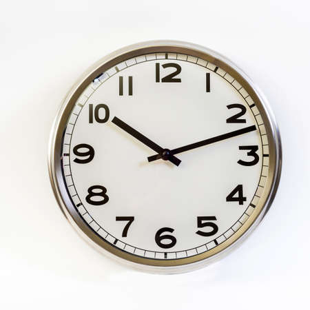 A steel clock on a white background shows ten hours and twelve minutes . Close up.の写真素材