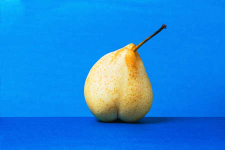 Ripe pear close- up on a blue background. The concept of healthy eating.の写真素材