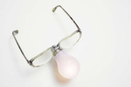 Close- up of an incandescent light bulb in the form of a human nose with glasses. The concept of the idea of genius and creative thinking.の写真素材