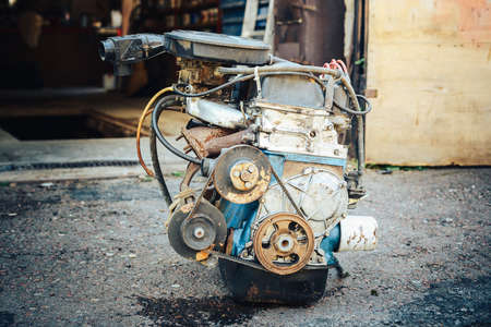 Close-up of an old engine removed from the car and lying near the garage.の写真素材
