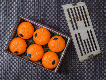 Decorative wooden box with candles in the form of tangerines on a dark background.の写真素材