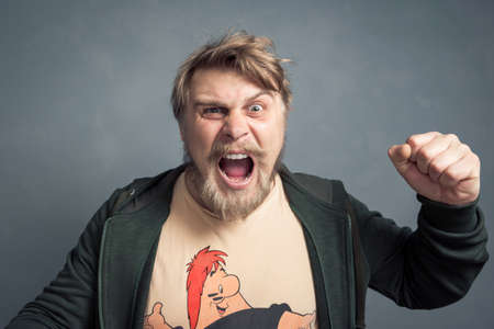 A portrait of a bearded guy with a raised hand and a clenched fist shouting Yes. The concept of luck, leadership and victory.の写真素材
