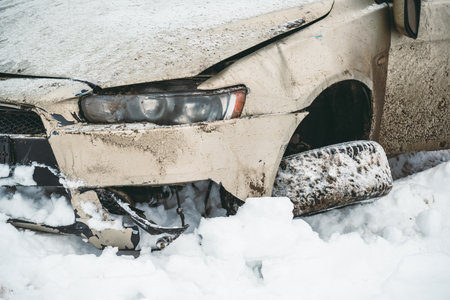 The car overturned on a snowy road and got on its wheels. Close-up of a broken car after an accident with a torn wheel, flying off the road at high speed.の写真素材