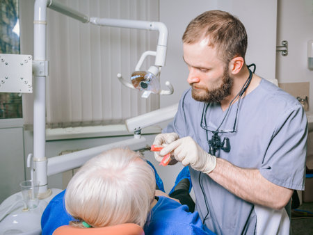 An elderly woman at the reception of a young male dentist. Fitting of the false jaw.の写真素材